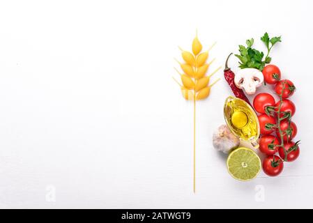 Trockene Pasta mit frischem Gemüse und Gewürzen. In Form eines Weizenspießchens auf Holzgrund. Draufsicht. Kopierbereich. Stockfoto