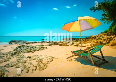 Kamala Beach, Phuket, Thailand: Sonnenliegen mit am Strand leerem Sonnenschirm mit idyllischem Blick über den Ozean mit blauem Himmel. Stockfoto