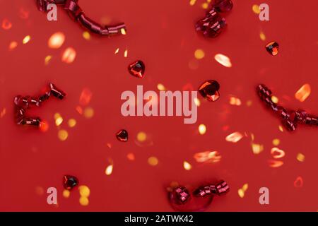 Roter Hintergrund mit verstreuten Kristallherzen und roten Saiten mit Lichter Bokeh. Valentinstag Stockfoto