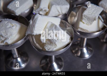 Weiße Eiscreme in Metallware im Tablett Selective Focus. Edelstahl-Eisbecher, die im angeordnet sind. Eiscreme in zwei Retro-Metallschüsseln auf einem Stockfoto