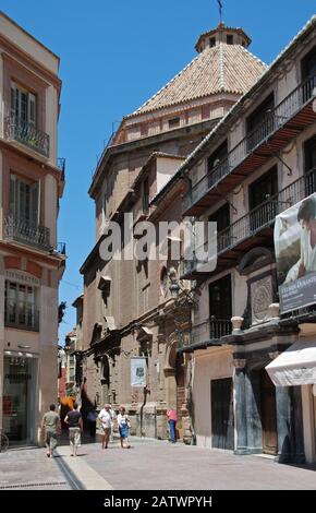 Blick auf die Kirche Heiliger Christus der Gesundheit in der Nordwestecke des Verfassungsplatzes mit Menschen, die die Umgebung genießen, Málaga, Spanien. Stockfoto