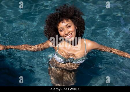 Junge Frau lächelt im Schwimmbad Stockfoto