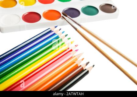 Farbstifte, ein Satz von Aquarellfarben und Pinsel werden auf weißem Hintergrund isoliert Stockfoto
