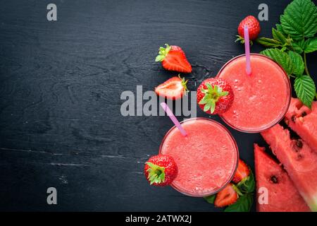 Frischer Cocktail aus Wassermelone und Erdbeeren. Minze, Eis. Auf einem Holzbrett. Draufsicht. Freier Speicherplatz für Ihren Text. Stockfoto