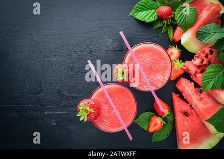 Frischer Cocktail aus Wassermelone und Erdbeeren. Minze, Eis. Auf einem Holzbrett. Draufsicht. Freier Speicherplatz für Ihren Text. Stockfoto