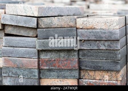 Stücke aus weißem, grauem, buntem Granit und Marmor. In quadratische Platten schneiden, die für die Konstruktion und Dekoration verwendet werden. In einem Lagerhaus für weitere Lagerung gestapelt Stockfoto