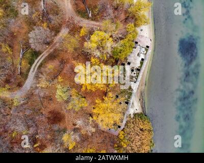 Drone Bild von heruntergekommenen verlassenen konkrete Lastkahn auf River Bank im Herbst Verfallende neben einem Fluss. Stockfoto