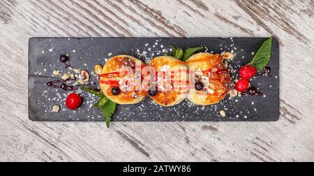 Süße Donuts mit Marmelade auf dem Küchenbrett. Ein schlichter Holzhintergrund. Köstliches Dessert im Restaurant. Stockfoto