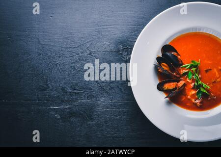 Cremige Suppe aus Tomaten und Meeresfrüchten mit Muscheln. Auf Holzgrund. Draufsicht. Freier Speicherplatz für Ihren Text. Stockfoto