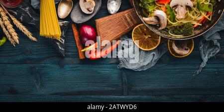 Asiatische Küche. Risotto mit Garnelen Nudeln mit Gemüse. Meeresfrüchte. Auf einem Holztexturhintergrund. Draufsicht. Freier Speicherplatz. Stockfoto