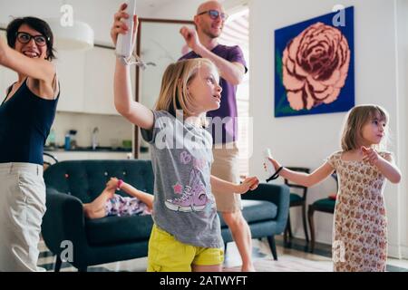 Familie tanzt zusammen in einem Videospiel - gesunder Lebensstil, Zusammengehörigkeit, Spielkonzept Stockfoto