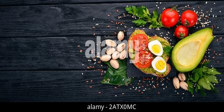 Sandwich mit Wachteleiern, Avocados, Kirschtomaten und Pistazien. Auf Holzgrund. Draufsicht. Freier Speicherplatz für Ihren Text. Stockfoto