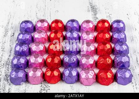 Geschenkschokolade mit Folienüberdacht. Süßes Dessert für Liebhaber. Weißer Holzhintergrund. Stockfoto