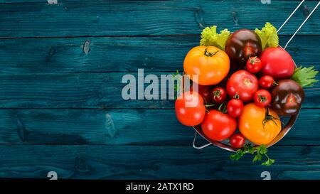 Frische Tomaten in einem Metallkorb. Auf Holzgrund. Draufsicht. Kopierbereich. Stockfoto