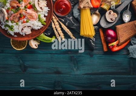 Asiatische Küche. Risotto mit Garnelen Nudeln mit Gemüse. Meeresfrüchte. Auf einem Holztexturhintergrund. Draufsicht. Freier Speicherplatz. Stockfoto