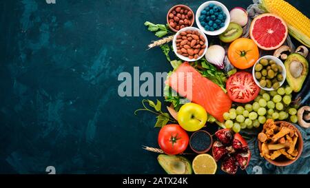 Ein Set gesunder Speisen auf einem Steintisch. Fisch, Gemüse, Obst, Nüsse, Beeren, Pilze. Draufsicht. Freier Speicherplatz für Text. Stockfoto