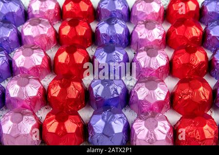 Geschenkschokolade mit Folienüberdacht. Süßes Dessert für Liebhaber. Weißer Holzhintergrund. Stockfoto