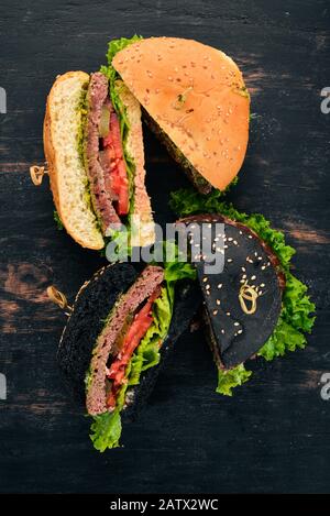 Lecker gegrilltes home Burger mit Rindfleisch, Tomaten, Käse, Gurken und Salat gemacht. Ansicht von oben mit der Kopie Raum Stockfoto