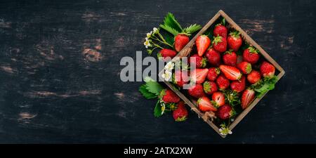 Frische Erdbeeren in einer Holzkiste. Auf Holzgrund. Draufsicht. Kopierbereich. Stockfoto
