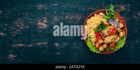 Bulgur mit Fleisch, Paprika, Kirschtomaten und Gemüse. Auf Holzgrund. Draufsicht. Kopierbereich. Stockfoto