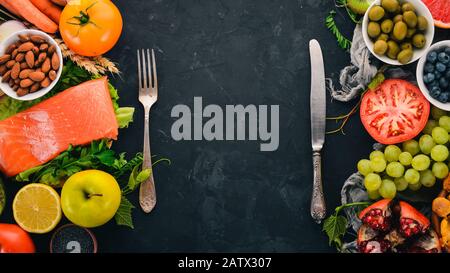 Ein Set gesunder Speisen auf einem Steintisch. Fisch, Gemüse, Obst, Nüsse, Beeren, Pilze. Draufsicht. Freier Speicherplatz für Text. Stockfoto