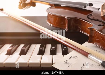 Geigenbogen und Noten auf Klaviertasten. Konzept der Interpretation von Klaviermusik und Streichinstrumenten. Vorderansicht. Horizontale Zusammensetzung. Stockfoto