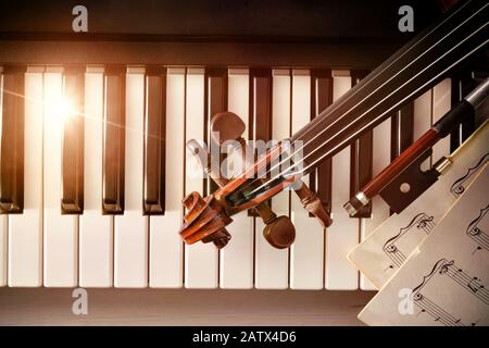 Geigenpegbox Bogen und Noten auf Klaviertasten. Konzept der Interpretation von Klaviermusik und Streichinstrumenten. Draufsicht. Horizontale Zusammensetzung. Stockfoto