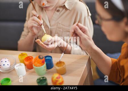 Nahaufnahme der zweiköpfigen Familie, die mit bunten Farben am Tisch sitzt und Ostereier schmückt Stockfoto