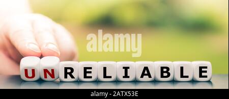 Hand dreht Würfel und ändert das Wort "unzuverlässig" in "haftbar". Stockfoto