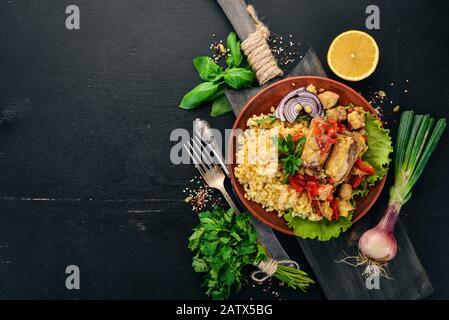 Bulgur mit Fleisch, Paprika, Kirschtomaten und Gemüse. Auf Holzgrund. Draufsicht. Kopierbereich. Stockfoto