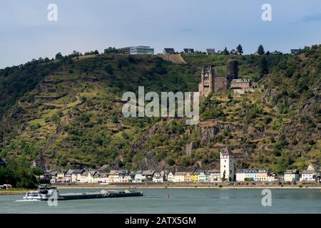 SANKT GOARSHAUSEN, DEUTSCHLAND - 06. JULI 2019: Frachtschiff, das am Rhein vorbei an St. Goarshausen und Schloss Katz fährt Stockfoto