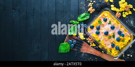 Haferflocken mit Blaubeeren und Joghurt. Gesunde Ernährung. Lunchboxen. Auf schwarzem Holzhintergrund. Draufsicht. Freier Speicherplatz für Text. Stockfoto