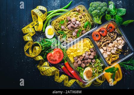 Pasta und Buchweizen mit Fleisch und frischem Gemüse. Gesunde Ernährung Essen. Mittagsboxen. Auf schwarzem Holzhintergrund. Draufsicht. Freier Speicherplatz für Text. Stockfoto