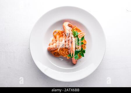 Teigwaren und Tigergarnelen in Tomatensauce. Traditionelle italienische Küche. Auf Holzgrund. Draufsicht. Freier Speicherplatz für Ihren Text. Stockfoto
