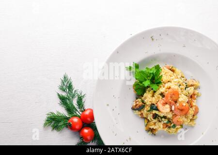 Risotto mit Garnelen. Auf einer hölzernen Hintergrund. Ansicht von oben. Freier Platz für Ihren Text. Stockfoto