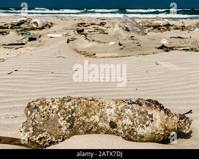 Plastikflaschen und anderer Müll, der auf die Sandküste geworfen wird, Müll am Meeresstrand, ökologisches Problem. Umweltverschmutzung. Schmutziger Sandstrände Stockfoto