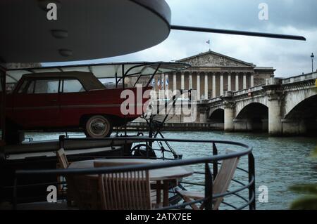 PARIS AUTO UND BOOT - EIN AMPHIBISCHES AUTO AUF EINER LUXURIÖSEN PÉNICHE VOR DEM PARLAMENTSGEBÄUDE "CHAMBRE DES DÉPUTÉS" UND DER BRÜCKE LA CONCORDE AM FLUSS LA SEINE PARIS FRANCE © F.BEAUMONT Stockfoto