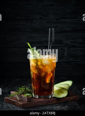Leckerer alkoholischer Cocktail. Cola, Whisky, Gurke und Eis. Auf Holzgrund. Draufsicht. Stockfoto