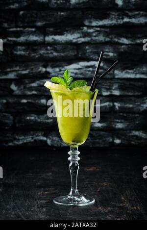 Tropisch-Grüner Alkoholischer Cocktail. Rum, Minze und Ananassaft. Alkoholischer Cocktail im Glas. Auf Holzgrund. Draufsicht. Freier Speicherplatz. Stockfoto