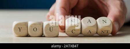 Weitsichts Bild von männlicher Hand Ändern einer Can-Nachricht Sie können sich nicht bei einer You CAN-Nachricht anmelden. Auf Holzdices geschrieben. Stockfoto