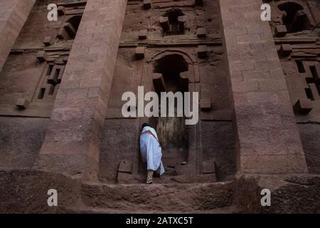 Lalibela, Äthiopien - November 2018: Mann in weiße traditionelle äthiopische Kleidung gekleidet, die an der ausgegrabenen Felsenkirchenkirche in Lalibela bettet. Stockfoto