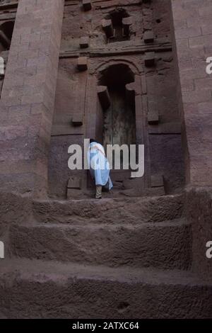 Lalibela, Äthiopien - November 2018: Mann in weiße traditionelle äthiopische Kleidung gekleidet, die an der ausgegrabenen Felsenkirchenkirche in Lalibela bettet. Stockfoto