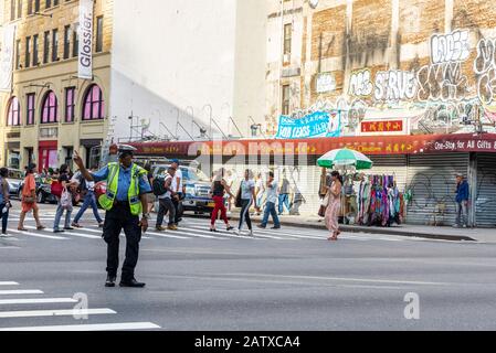 New York City, USA - 2. August 2018: Polizist, der den Verkehr lenkt, hebt die Hand in Manhattan, New York City, USA Stockfoto