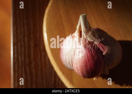 Ganzer Knoblauchkopf in der Schale auf dem sonnigen Holztisch. Stockfoto