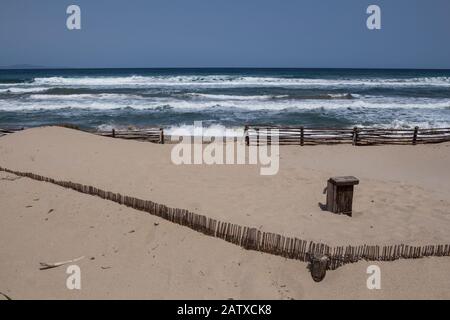 Kleiner Holzbrunnen mit Wasserhahn. Linie des Holzzauns, der die Dünen Sanddünen an der Küste des mittelmeeres auf der Insel Sar unterstützt Stockfoto