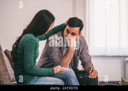 Der Mann ist traurig und depressiv, seine Frau tröstet ihn. Stockfoto