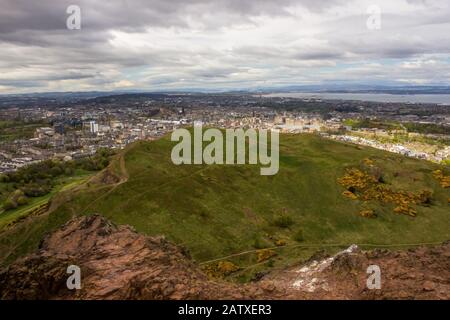 Blick vom Arthurs Seat über den Holyrood Park mit dem Stadtzentrum von Edinburgh und dem Firth of Forth im Hintergrund, Stockfoto