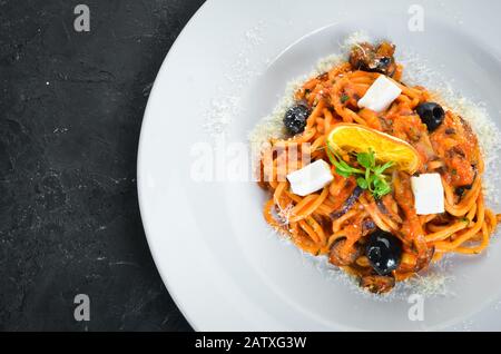 Spaghetti mit Tomaten, Oliven und Fetakäse auf einem Teller. Draufsicht. Freier Speicherplatz für Ihren Text. Stockfoto