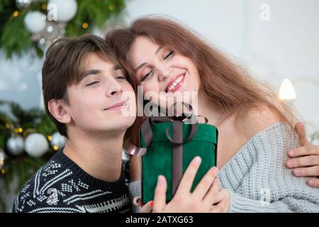 Ein Mann schenkt einer Frau ein Weihnachtsgeschenk. Mann und Frau in den Neujahrstagen. Lassen Sie sich in den Winterferien überraschen. Weihnachtsfeiertage Konzept. Stockfoto