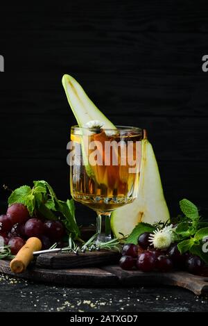 Heiße Wintergetränke. Heißer Weißwein mit Birne und Zimt. Im Glas. Draufsicht. Auf schwarzem Hintergrund. Stockfoto
